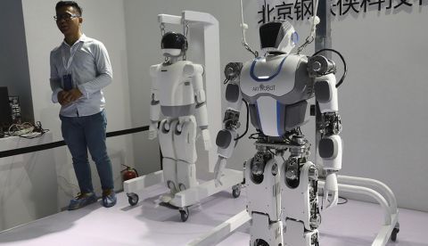 Un visitante posa junto a dos robots durante la Feria Mundial de Robots en Pekín (China). EFE/Archivo 