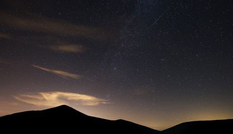 Una perseida o Lágrima de San Lorenzo atraviesa el cielo junto a la Vía Láctea sobre el municipio cántabro de San Miguel de Aguayo. EFE/Archivo
