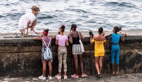 Jóvenes cubanos miran al mar desde el malecón de La Habana en enero de 2022. Shutterstock / anandoart