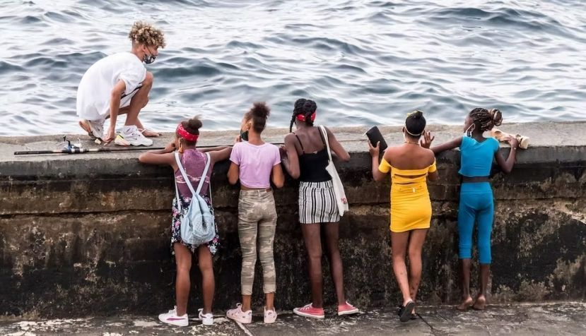 Jóvenes cubanos miran al mar desde el malecón de La Habana en enero de 2022. Shutterstock / anandoart