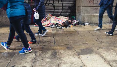 Una persona y un perro duermen en una calle de Barcelona un día lluvioso. Shutterstock / Bogdan Khmelnytskyi