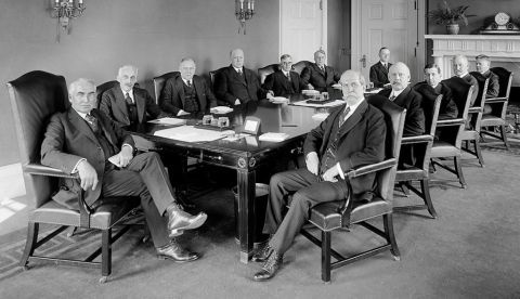 Constitución en 1921 del primer Gabinete del 29º presidente de Estados Unidos W. G. Harding, quien preside la mesa. A su derecha Charles E. Hughes, secretario de Estado. A su izquierda, Andrew W. Mellon, secretario del Tesoro. El cuarto por la derecha es Albert Fall, secretario de Interior, el primer miembro de un Gobierno estadounidense en entrar en prisión. / Wikipedia.