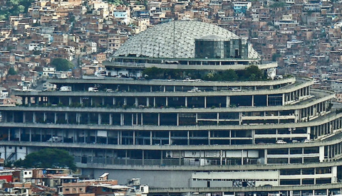  Edificio de hormigón de estilo brutalista rodeado de otros edificios. Edificio El Helicoide, en Caracas. Damián D. Fossi Salas/Wikimedia Commons