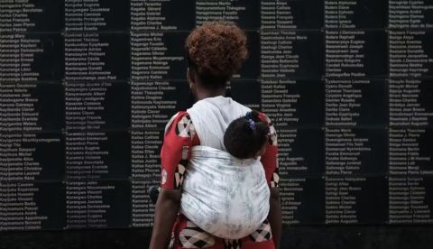 Una mujer con un niño en brazos observa un muro en Kigali con los nombres de las víctimas del genocidio de Ruanda de 1994. Yasuyoshi Chiba/AFP via Getty Images