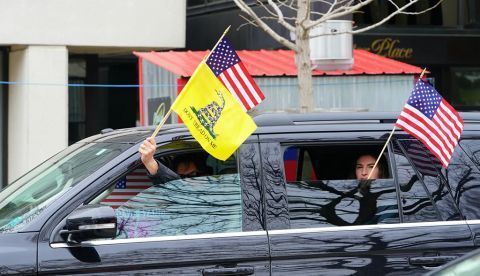 Un conductor enarbola las banderas de EE UU y la amarilla de Gadsden, asociada al libertarianismo, durante una manifestación motorizada contra el confinamiento domiciliario por la pandemia de covid-19 (Madison, Wisconsin, abril de 2020). Shutterstock / Aaron of L.A. Photography