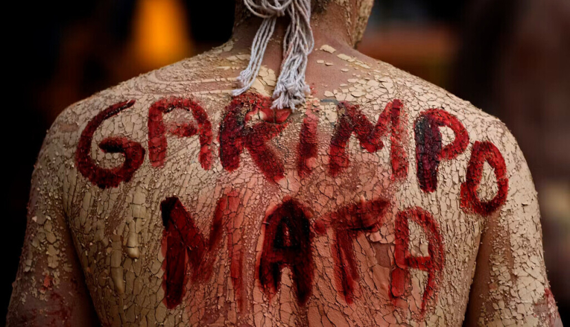 Un indígena yanomami protesta contra la minería ilegal en una manifestación en Brasilia, durante el gobierno de Bolsonaro, en 2022: la minería ilegal de oro puede propagar la malaria de diversas maneras, como con la tala de bosques en las riberas de los ríos y el transporte del parásito a otras zonas del país. AP Photo/Eraldo Peres