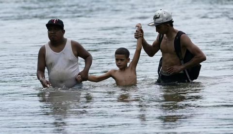 Migrantes vadean el río Tuquesa mientras atraviesan el Darien Gap. AP Photo/Arnulfo Franco
