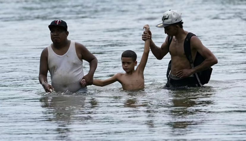 Migrantes vadean el río Tuquesa mientras atraviesan el Darien Gap. AP Photo/Arnulfo Franco