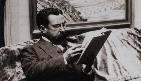 Marcel Sembat leyendo frente a un cuadro de Georgette Agutte. Fotografía de Henri Manuel hacia 1920. / Wikipedia