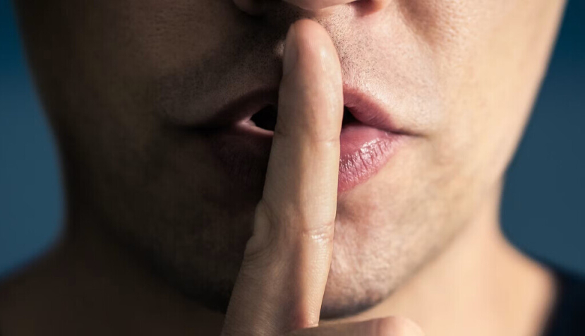  Un hombre se pone el dedo en los labios en ademán de mandar que se guarde silencio. Tero Vesalainen/Shutterstock