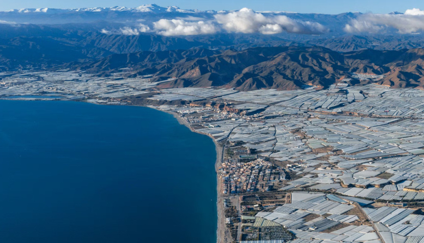  Vista de invernaderos junto a la costa con una cordillera de fondo Invernaderos en la costa de Almería (España). Mike Workman/Shutterstock