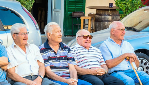 Grupo de ancianos italianos sentados en un banco en el centro de Scicli, Italia. Eddy Galeotti/Shutterstock