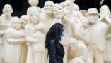 A woman wears a face mask as she walks by the sculpture ‘The Illuminated Crowd’ on a street in Montréal. Vulnerable people may benefit from measures like face masks even after the COVID-19 pandemic. THE CANADIAN PRESS/Graham Hughes
