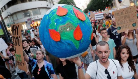 Un joven lleva un globo terrestre en llamas durante una manifestación por la emergencia climática. EFE/Kai Försterling/Archivo