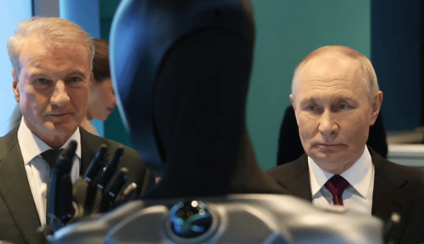 Sur cette photo diffusée par l’agence d’État russe Sputnik, Vladimir Poutine, accompagné de Guerman Gref, PDG de la Sberbank, première banque de Russie, visite la conférence internationale « Sber – AI Journey » à Moscou, le 19 novembre 2025. Il est accueilli par un robot anthropomorphe équipé d’une intelligence artificielle développé par la société technologique Sber (qui relève de la Sberbank). Sputnik/AFP