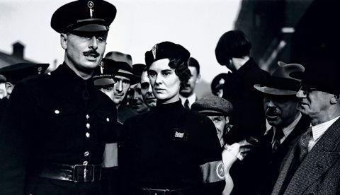Oswald Mosley (1896-1980), en primer plano a la izquierda, líder de la Unión Británica de Fascistas, marcha con sus camisas negras al East End de Londres". Habiendo sido previamente un político conservador e independiente, Mosley fue parte del gobierno laborista de 1929. Al dimitir, Mosley fue nombrado líder de la Unión Británica de Fascistas.
