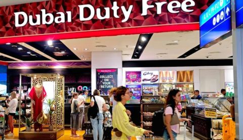  Gente con maletas junto a un establecimiento con el rótulo "Dubai duty free" Aeropuerto de Dubái. shanid chirammal house/Shutterstock