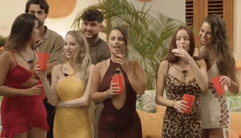  Un grupo de mujeres con vestidos ajustados se mira y habla entre ellas. Momento del programa televisivo La isla de las tentaciones. Mediaset.
